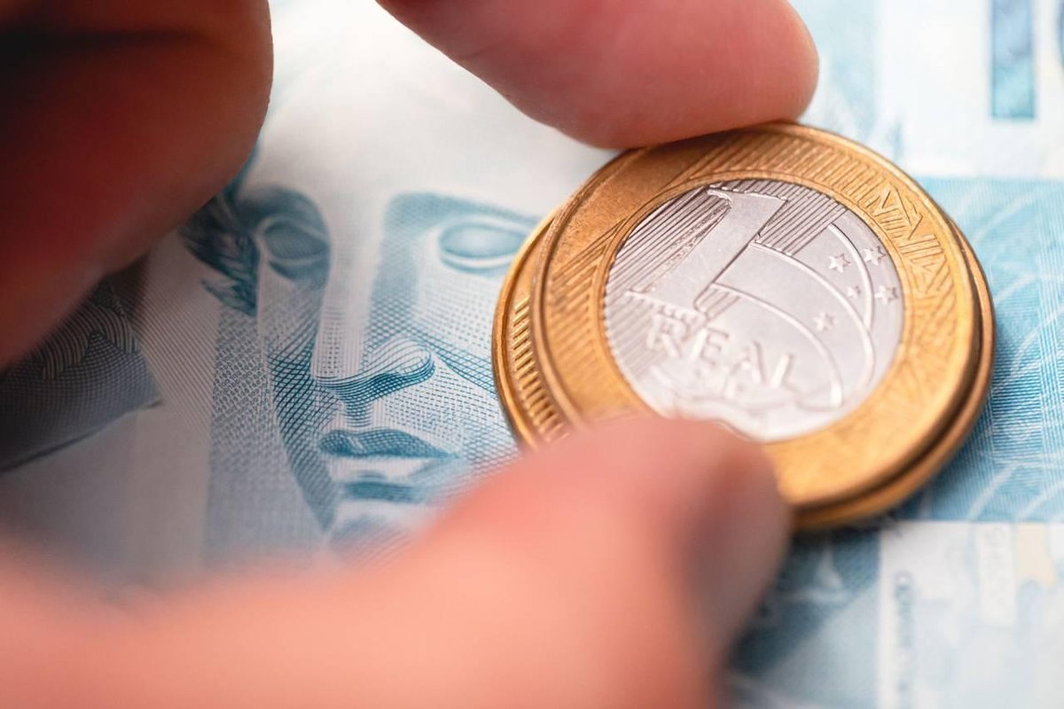 Moedas de um real sobre notas de 100 (Imagem gerada com auxílio IA/Leonardo Albertino)