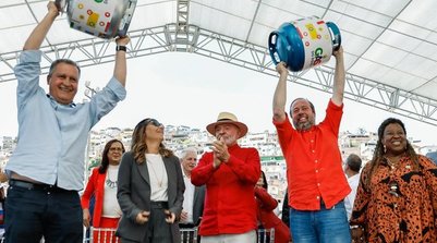 Os ministros Rui Costa e Alexandre Silveira levantam botijões de gás, em evento ao lado de Lula (Foto: Ricardo Stuckert / PR)